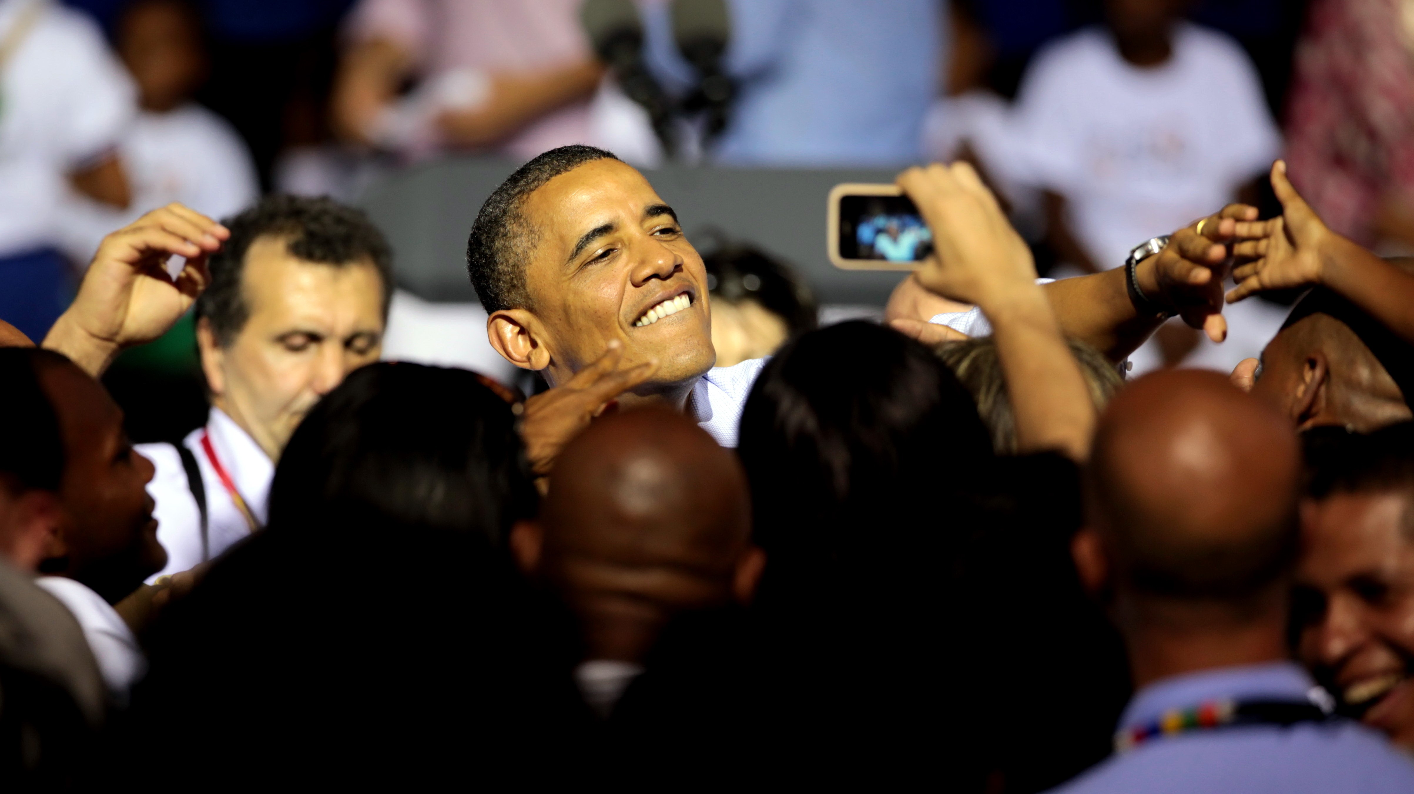 Obama_americký prezident_pozerá do mobilu_usmieva sa